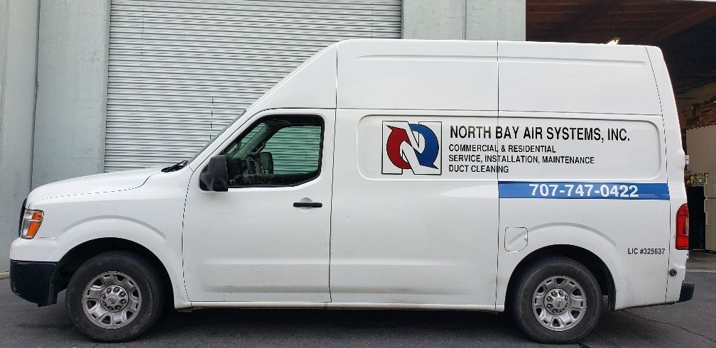 A white van is parked in front of a building.