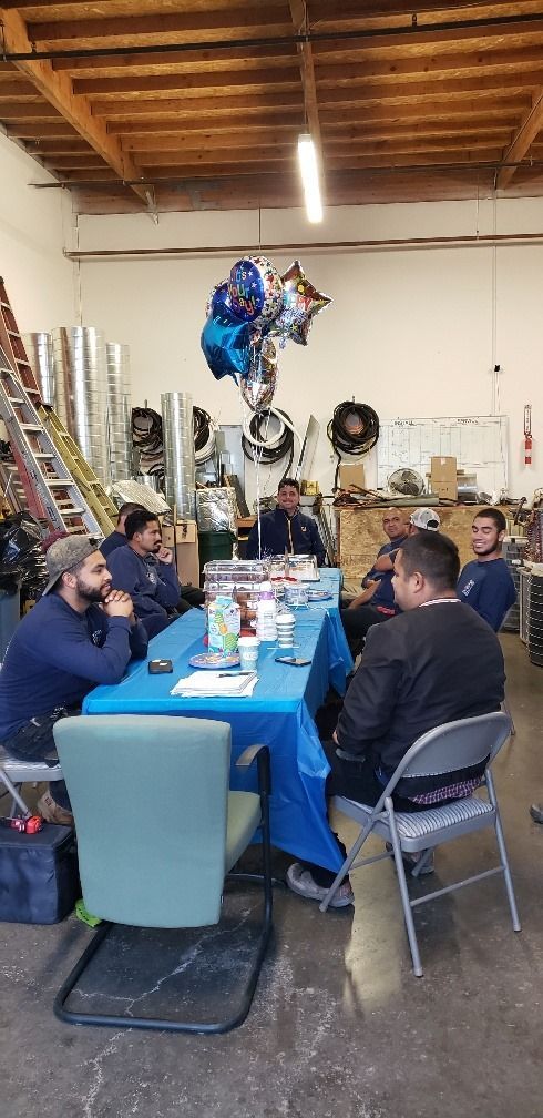 A group of men are sitting around a table in a garage.