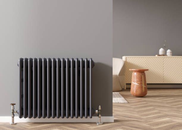 A radiator is sitting on a wooden floor next to a wall in a living room.