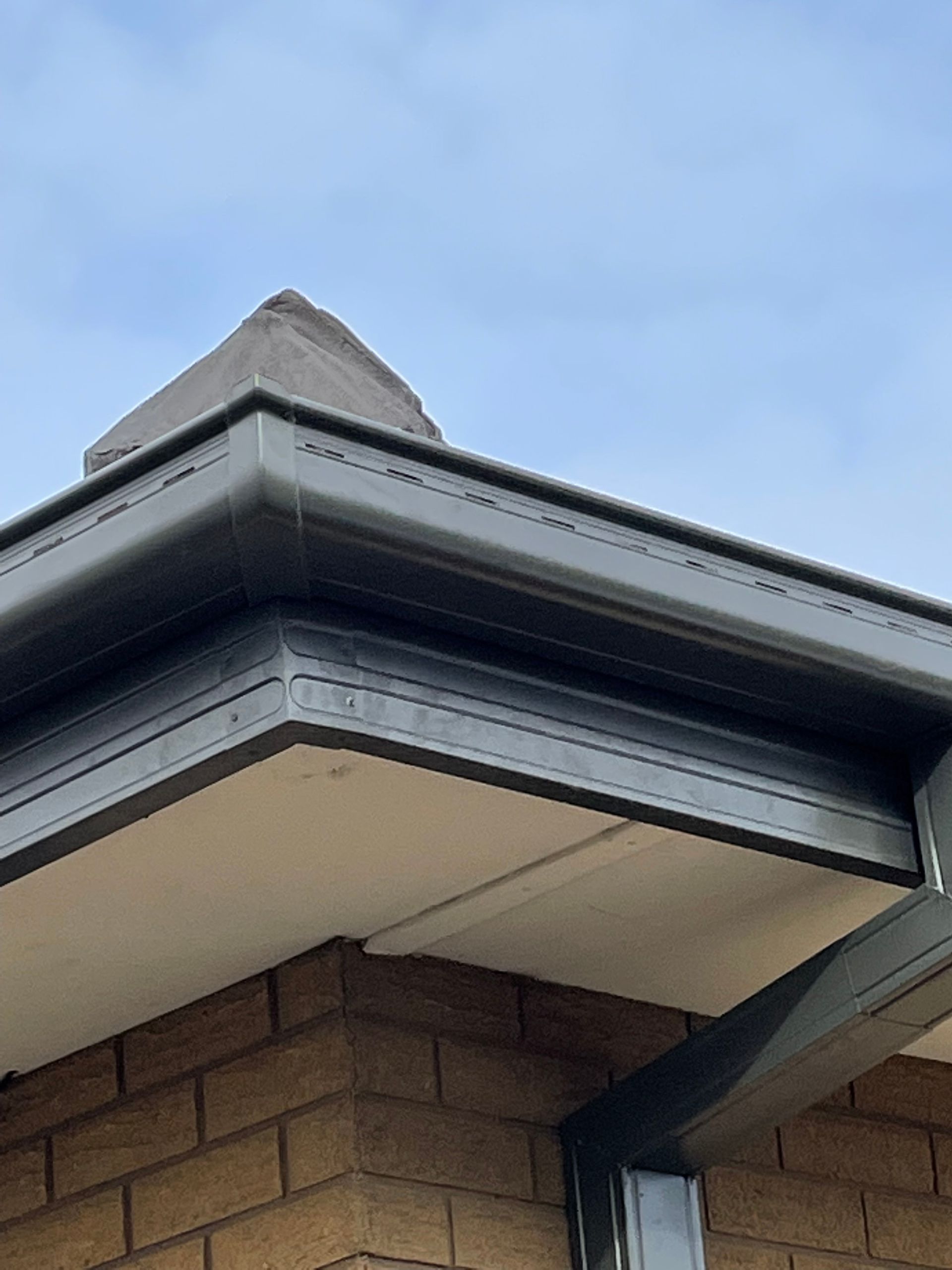 A gutter is sitting on top of a tiled roof next to a wooden fence.
