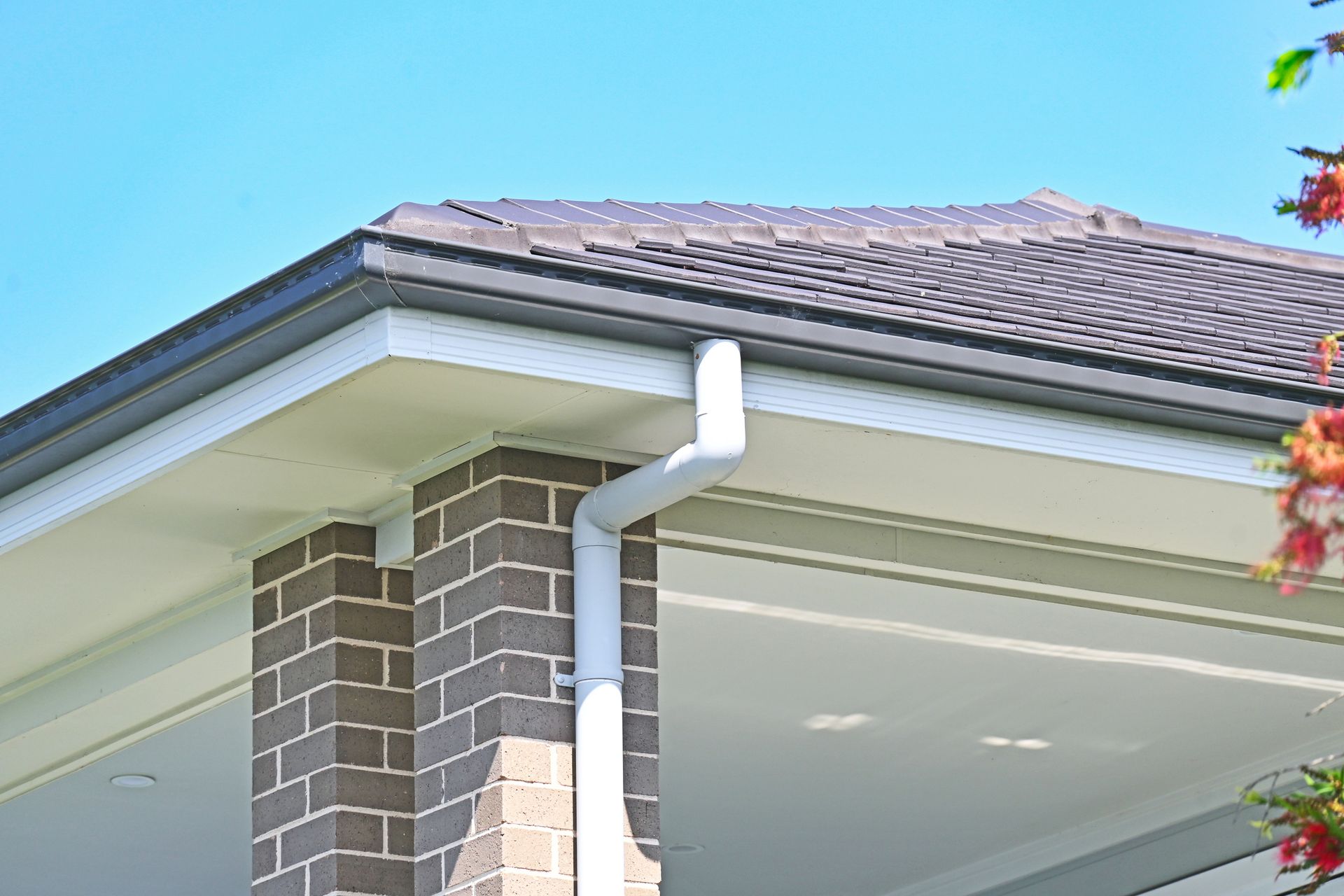 Brick pillar supports roof with dark tiles and white gutter