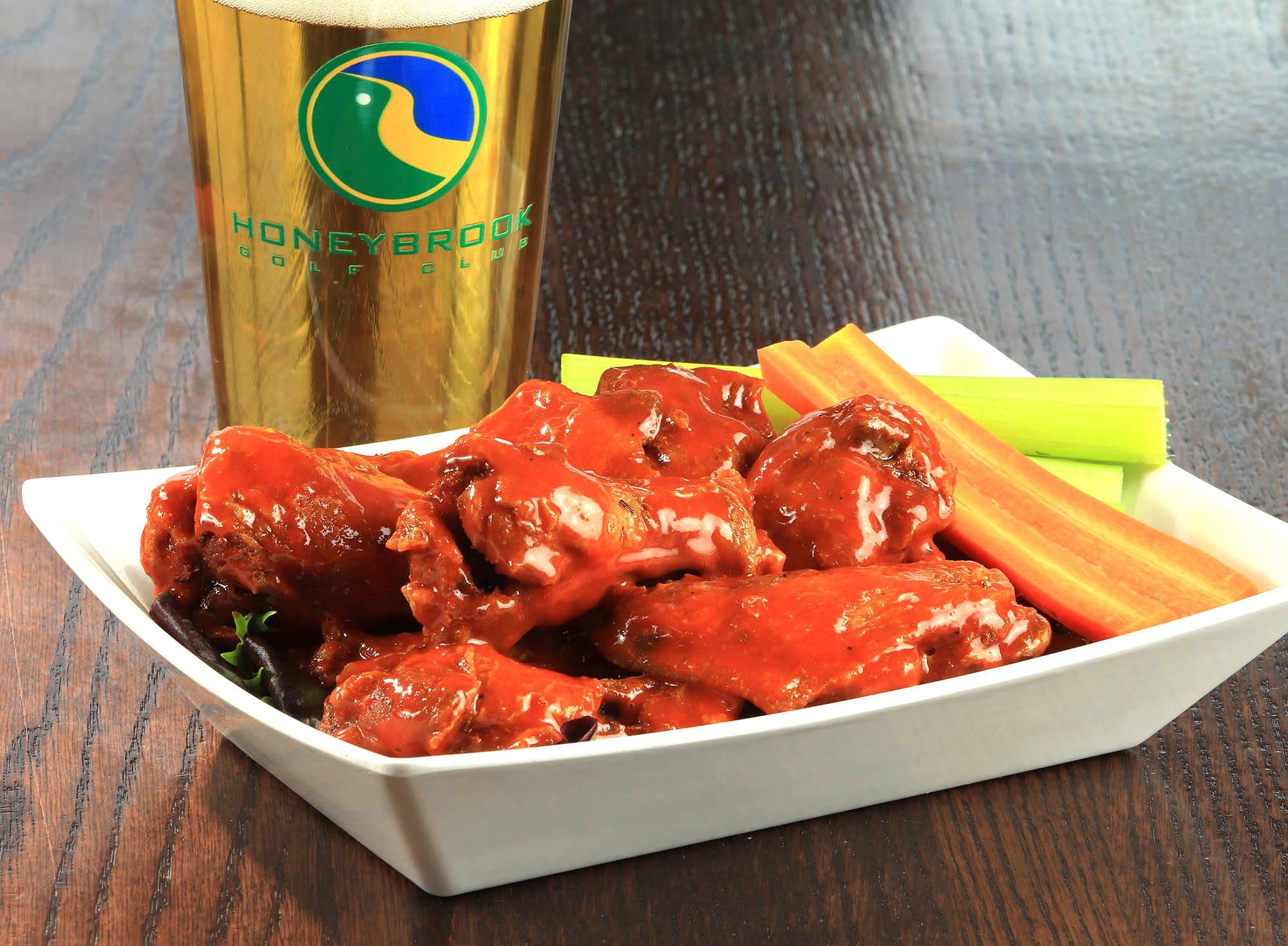 A plate of chicken wings next to a glass of beer