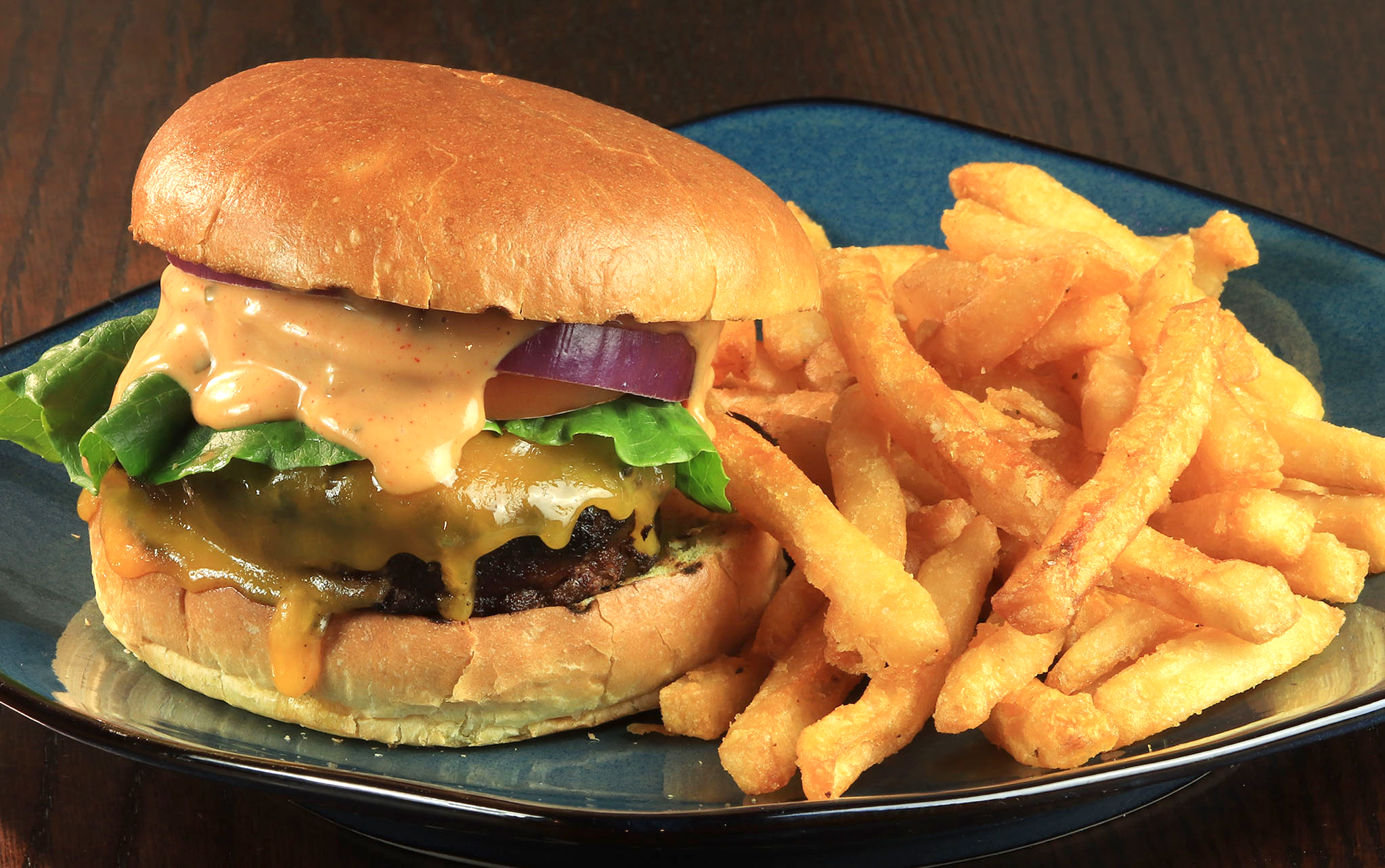 A hamburger and french fries on a blue plate