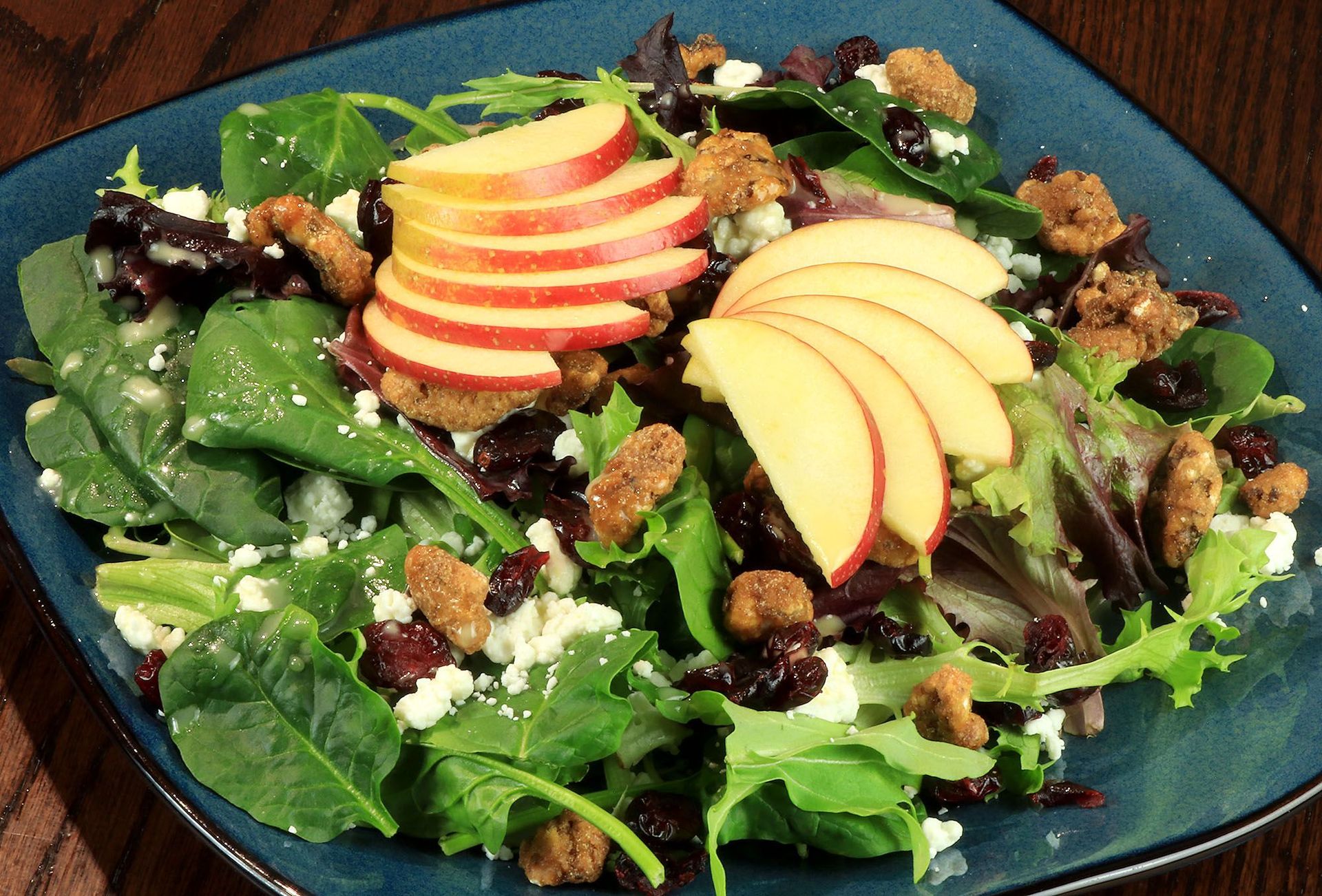 A salad with apples and cranberries on a blue plate