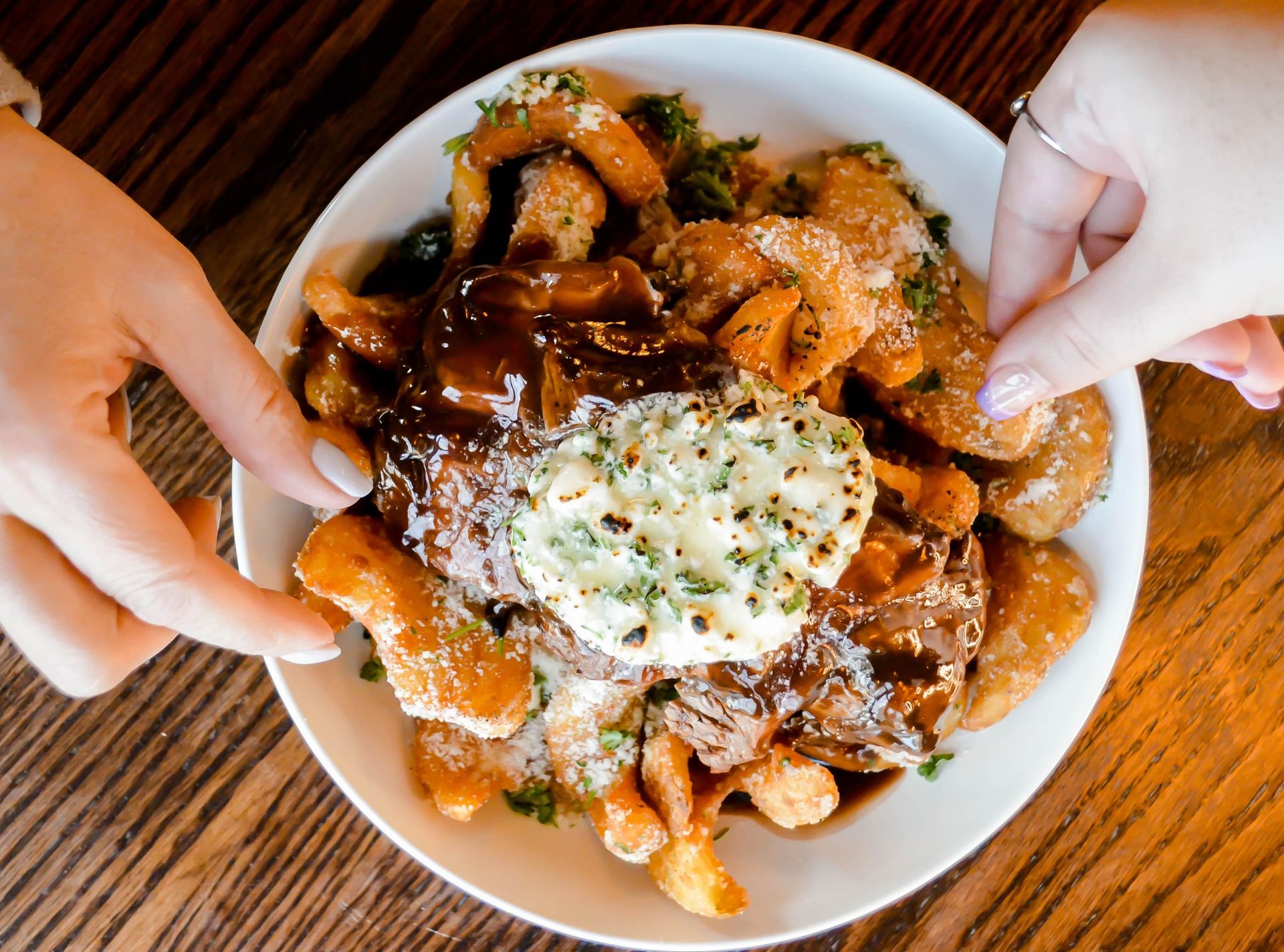 A person is holding a plate of food on a wooden table.