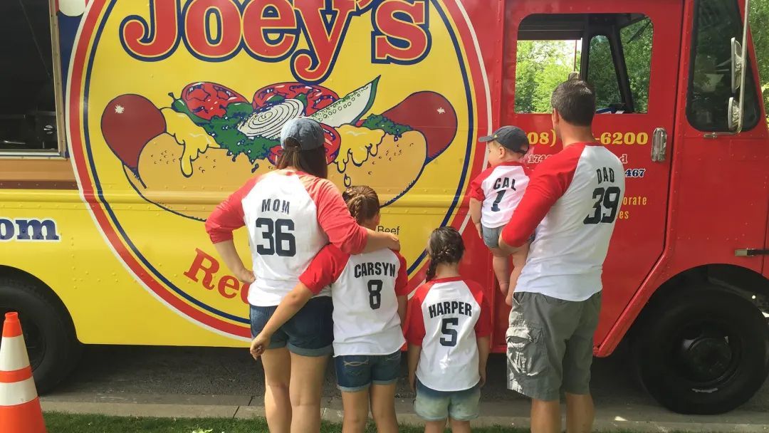 Family poses in matching baseball shirts in front of Joey's food truck.