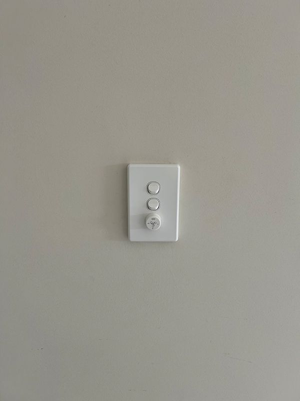 A White Light Switch is Hanging on a White Wall — AES Electrical Contracting In Winnellie, NT