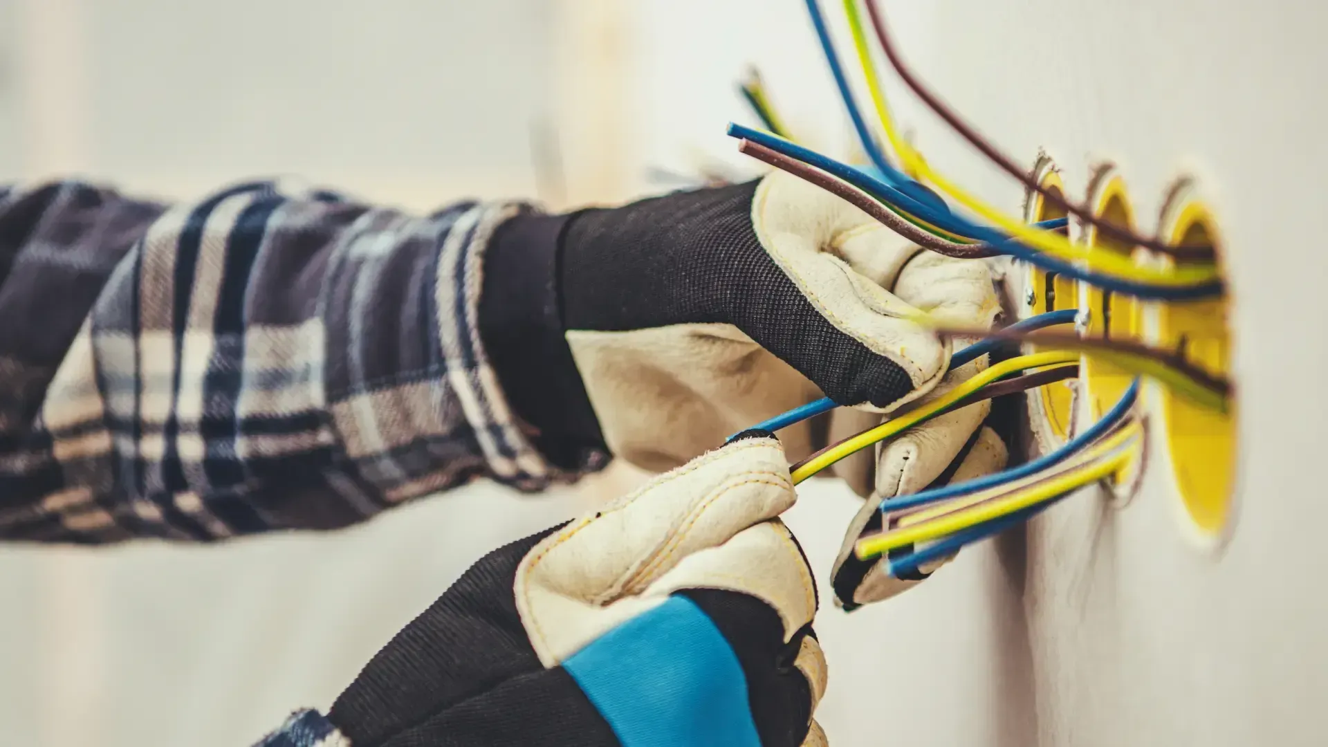 A person is installing electrical wires in a wall.