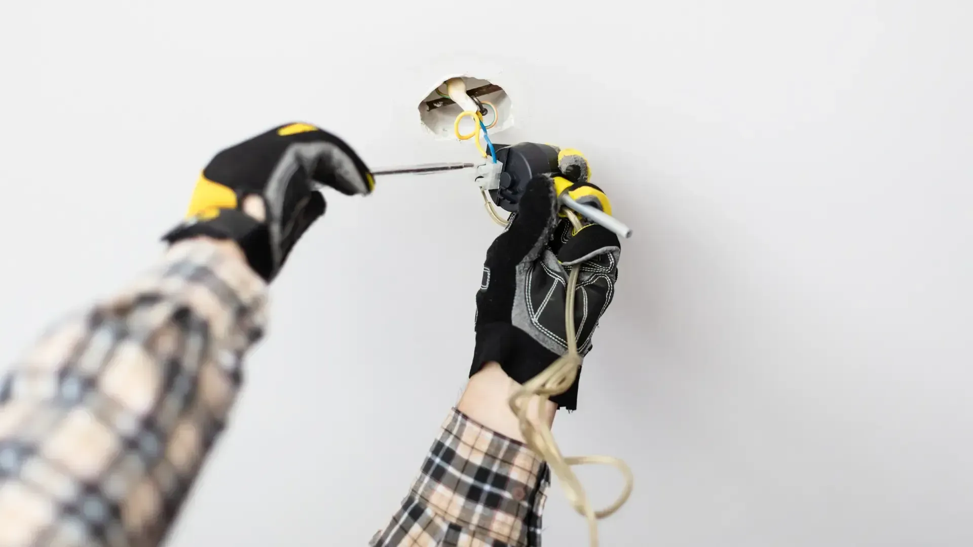 A person is installing a light fixture on a wall.