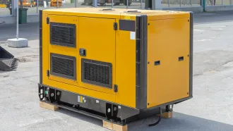 A yellow and black generator is sitting on top of a wooden pallet.