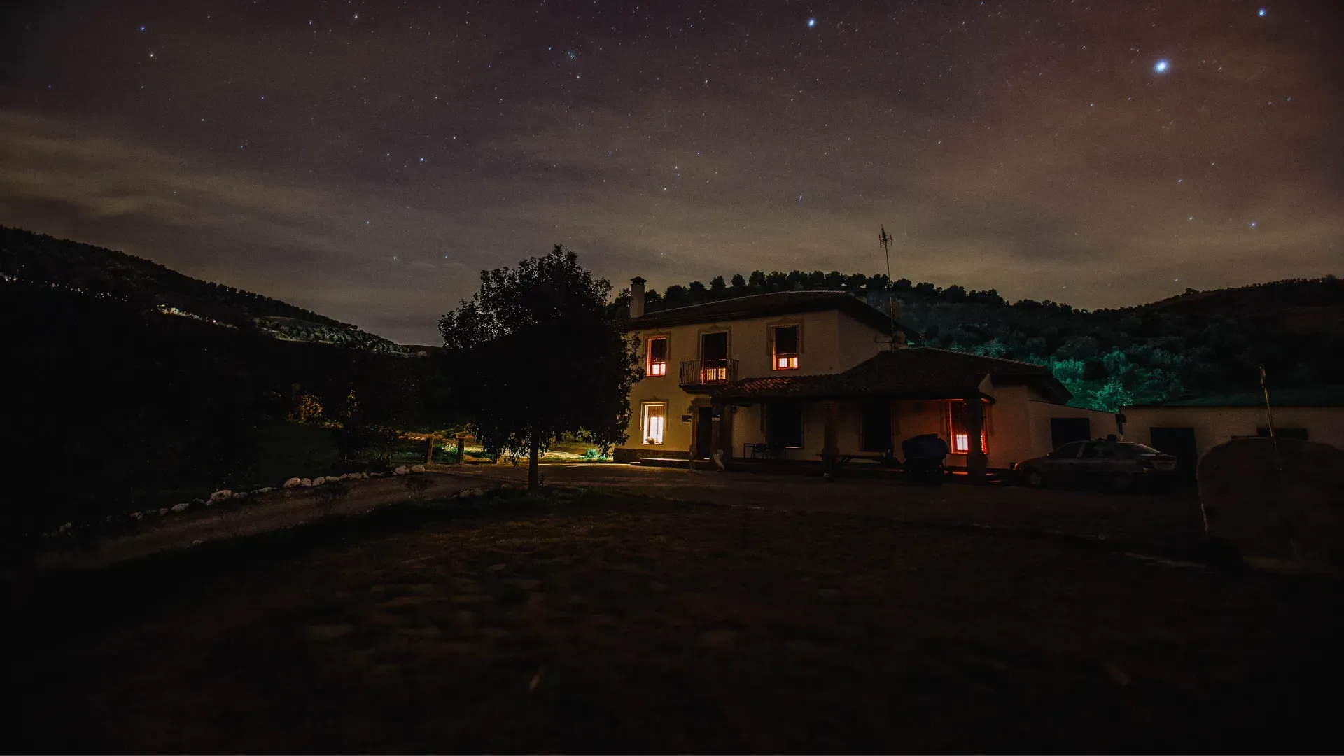 A house is lit up at night under a starry sky.