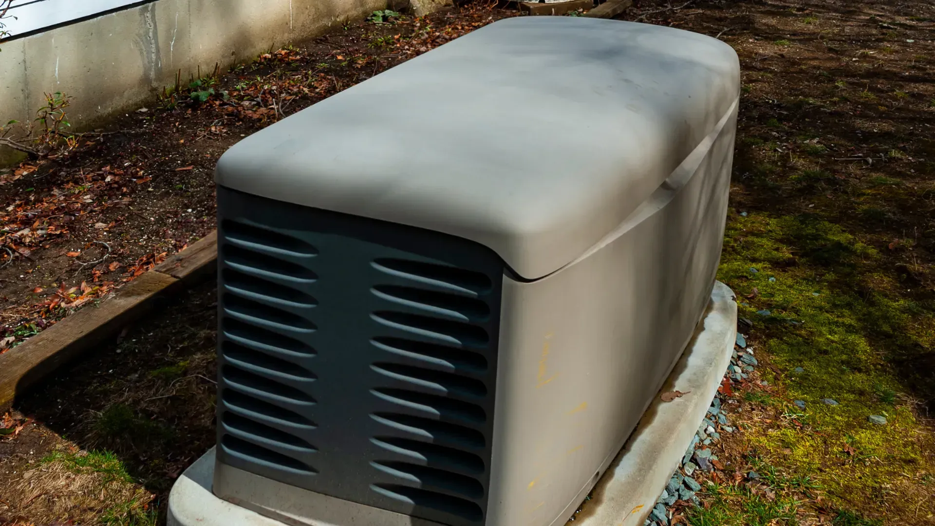 A generator is sitting on top of a concrete base in the grass.