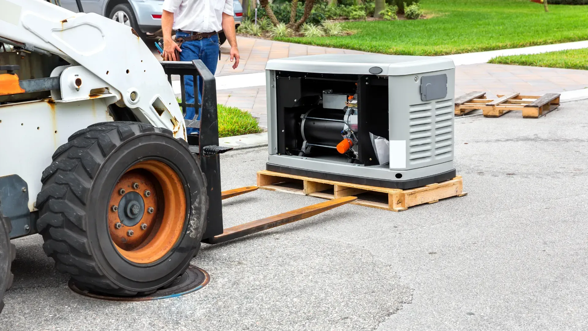 A forklift is carrying a generator on a wooden pallet.