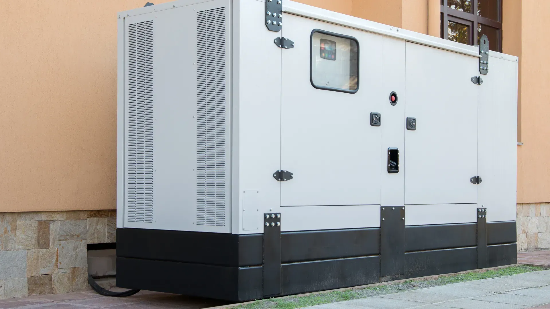 A large white generator is sitting outside of a building.