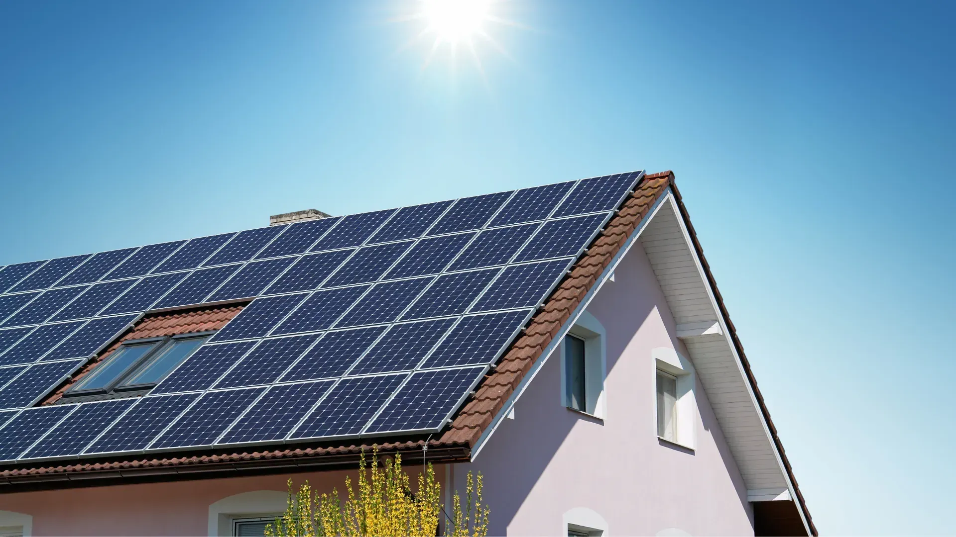 A pink house with solar panels on the roof.