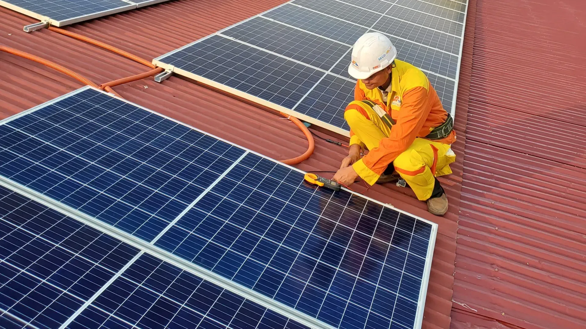 A man is installing solar panels on the roof of a building.