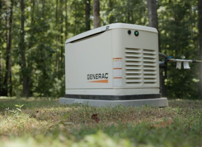 A generator is sitting in the middle of a grassy field.