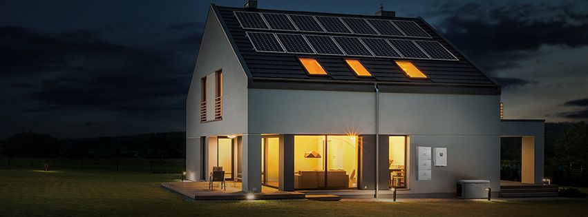 A house with solar panels on the roof is lit up at night.
