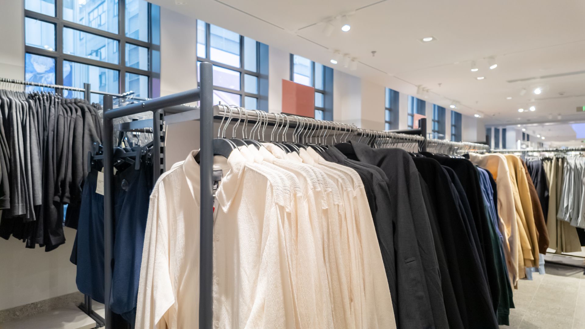 Stylish rack with neutral-toned shirts, blazers, and outerwear on display.