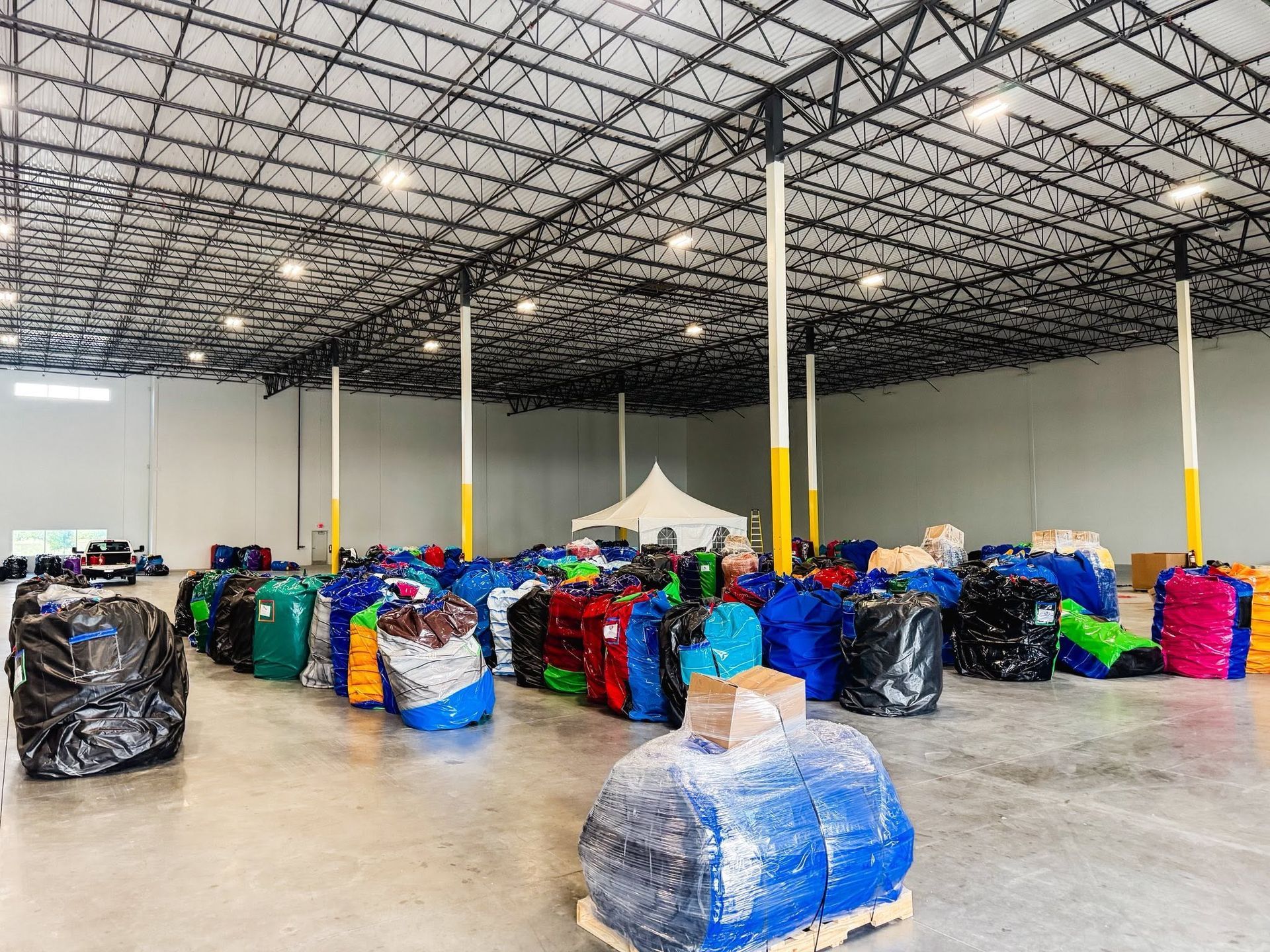 Warehouse floor with rows of colorful wrapped bales under a high metal ceiling