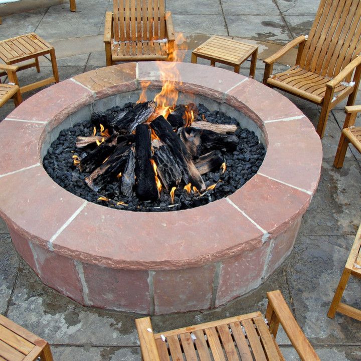 A fire pit is surrounded by wooden chairs and tables