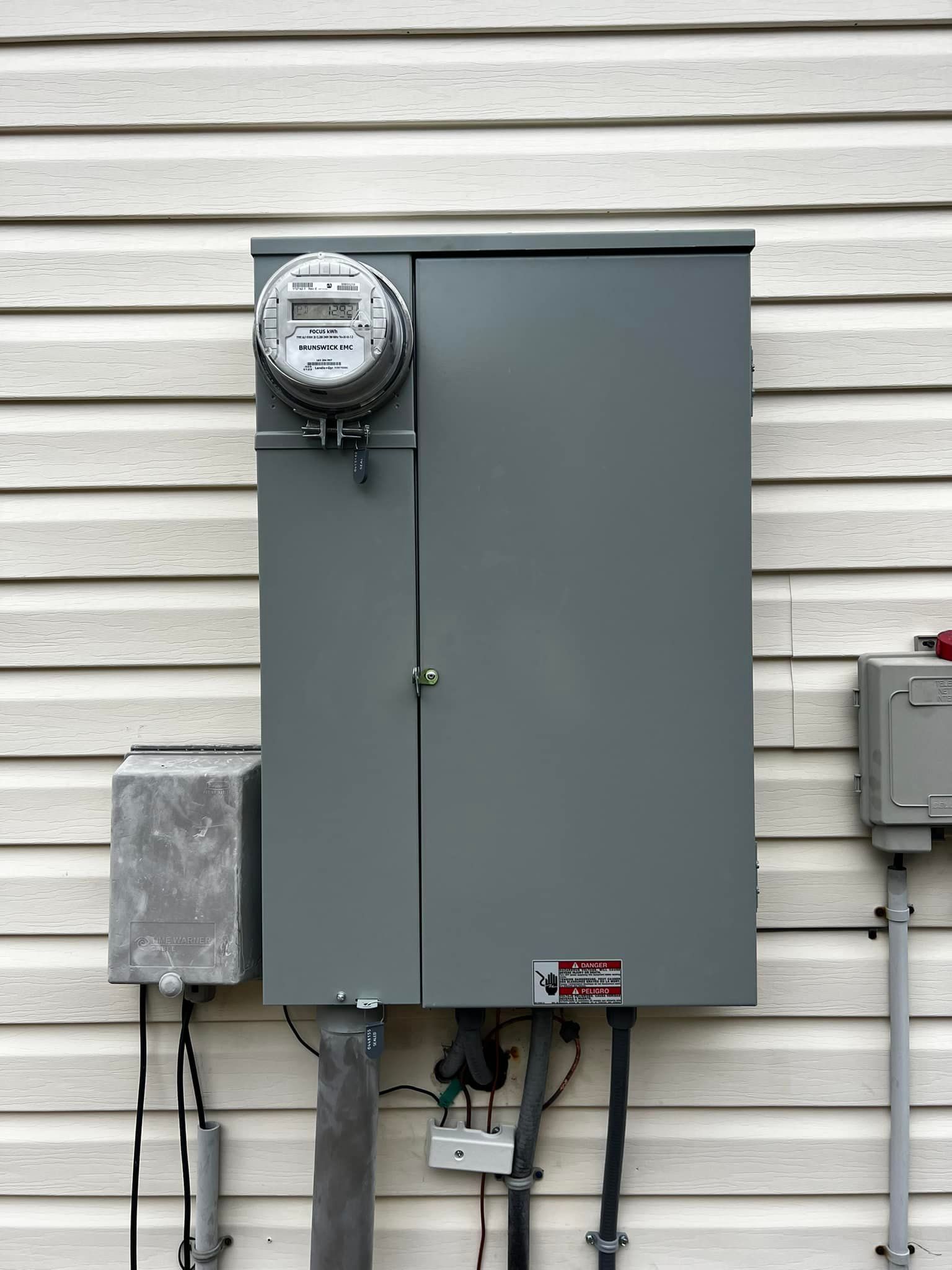Electrical box with meter, gray, mounted on white siding.
