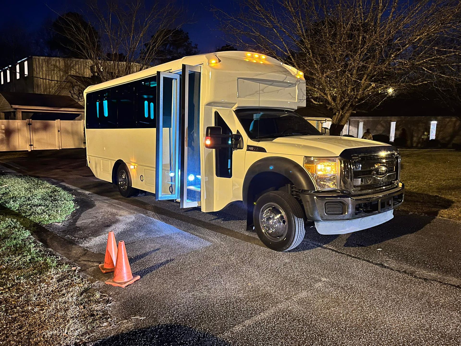 a white bus is parked in a driveway at night .