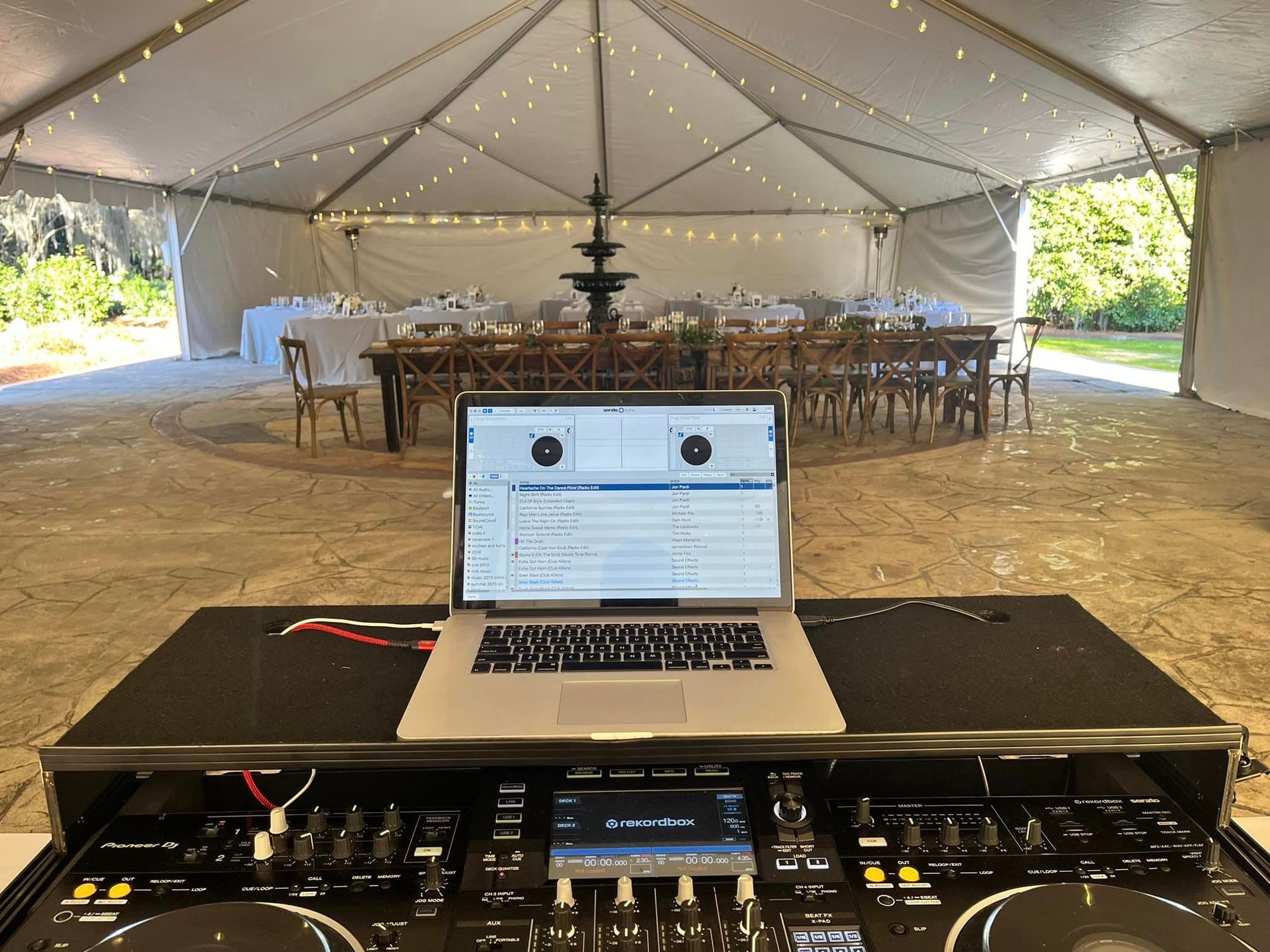 a laptop is sitting on top of a dj controller in front of a tent .