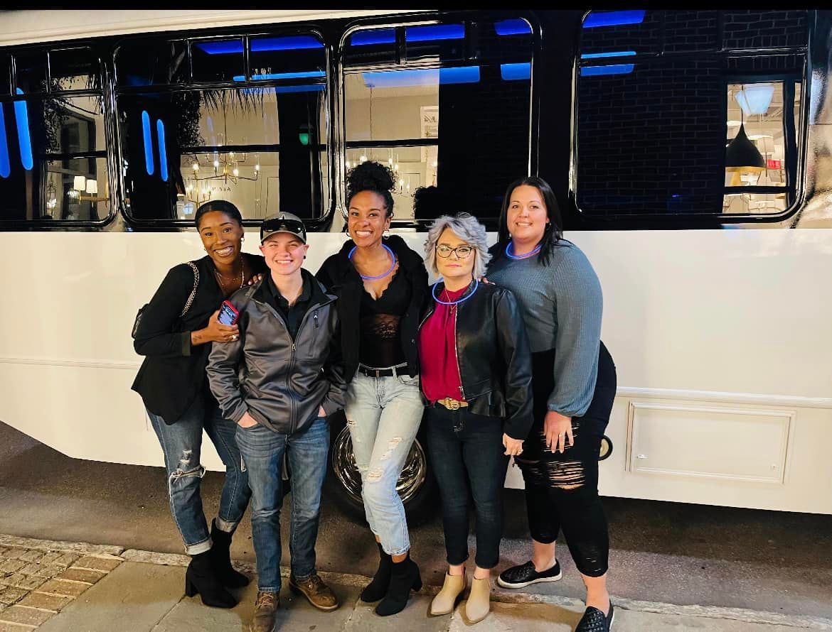a group of women are posing for a picture in front of a bus .