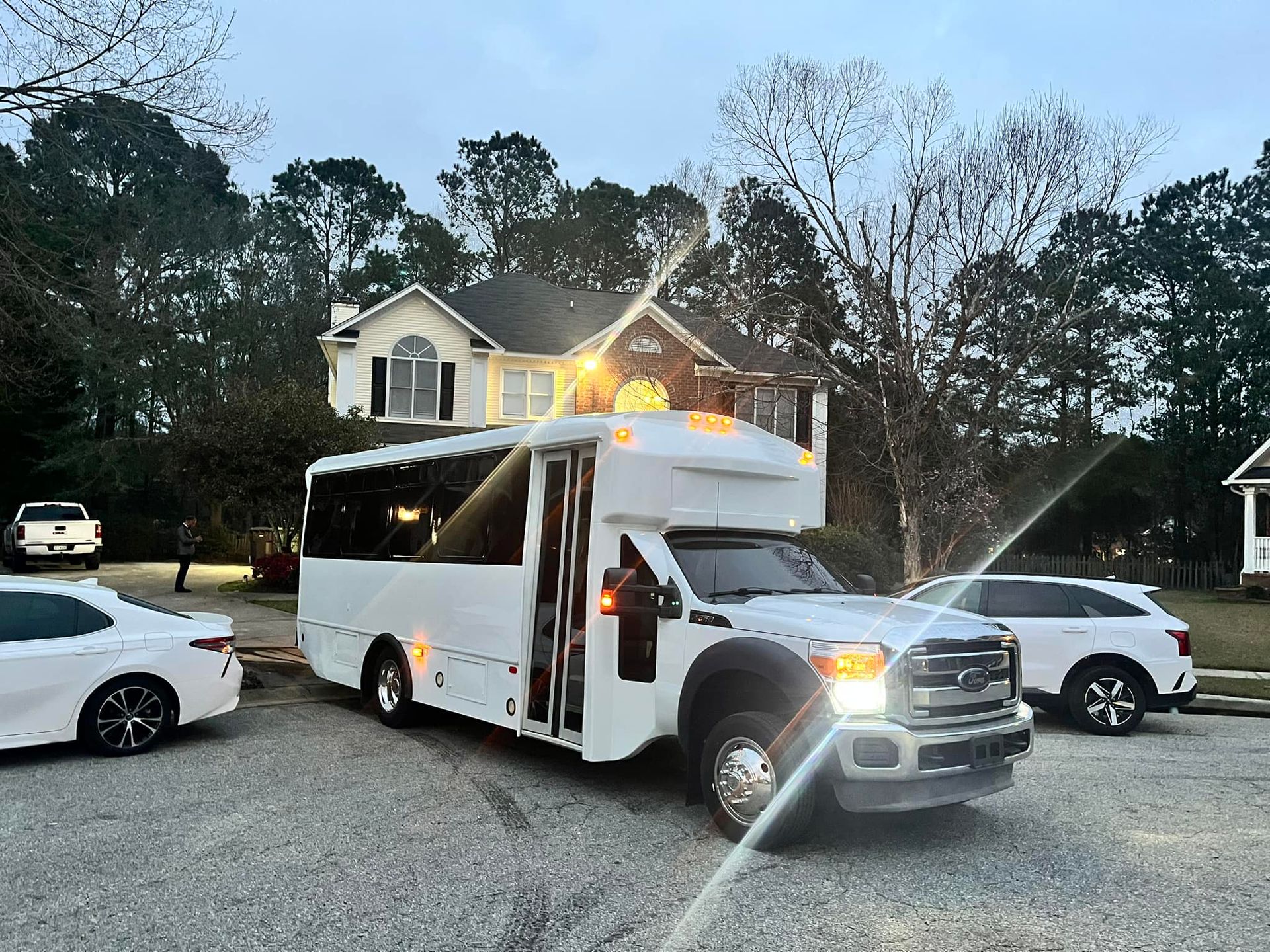a white bus is parked in front of a house .