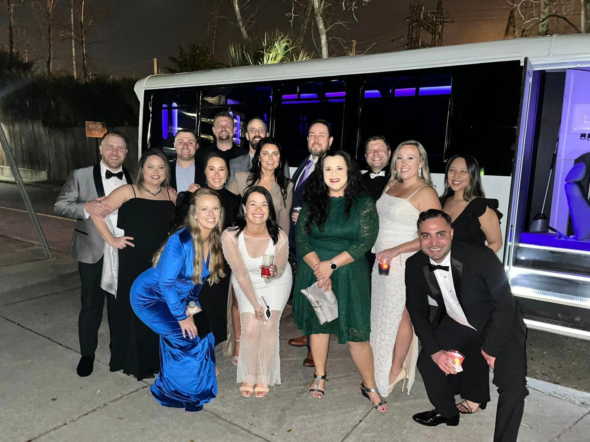 a group of people are posing for a picture in front of a limousine .