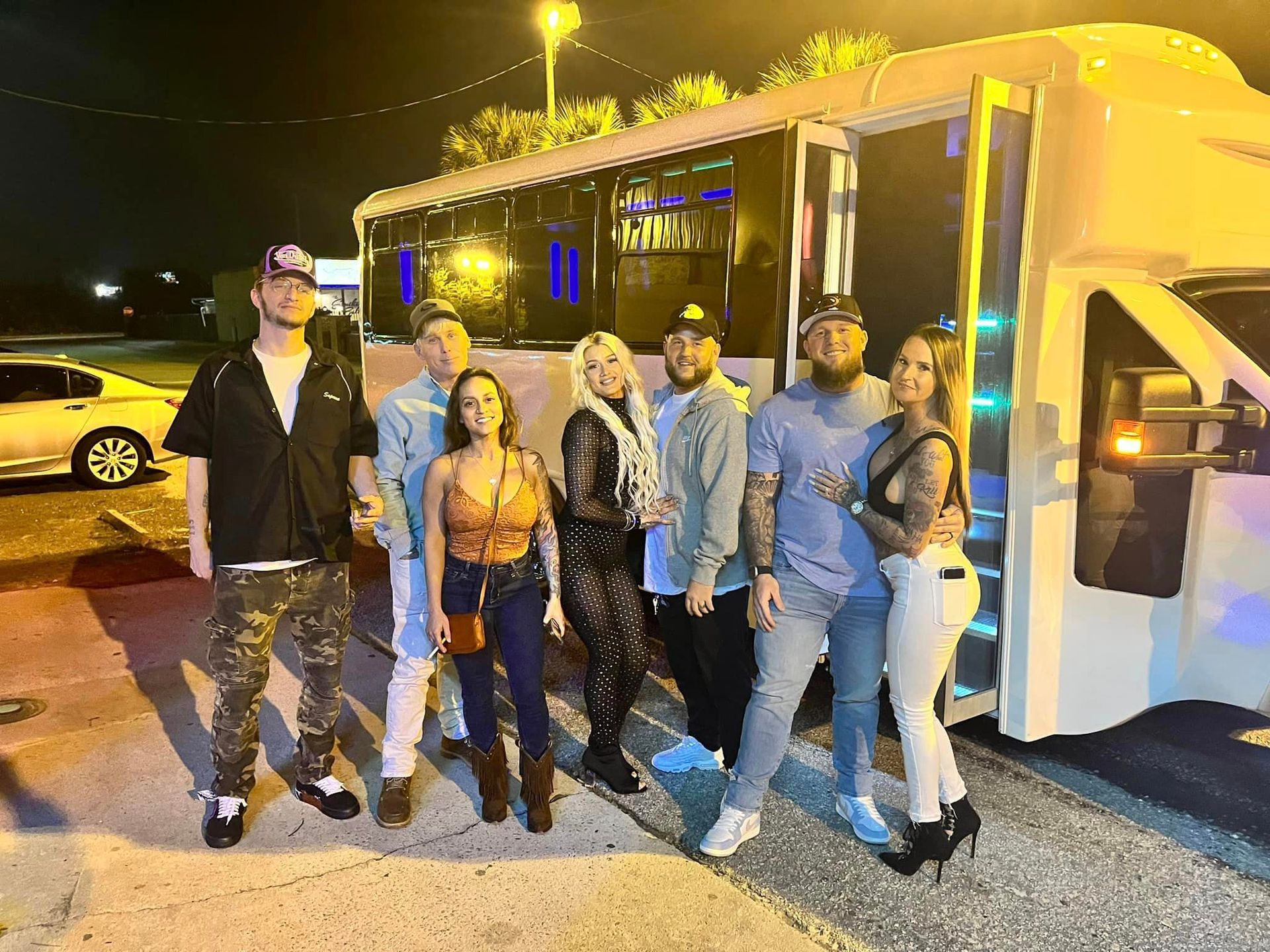 a group of people are standing in front of a shuttle bus at night .