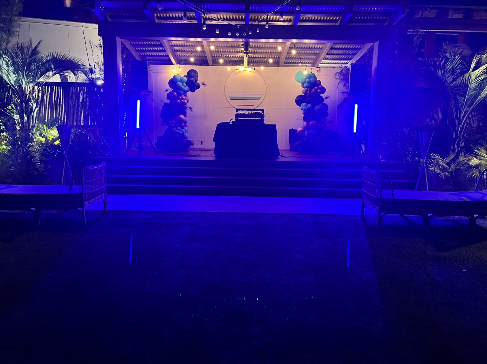 a stage with blue lights and balloons on it at night .