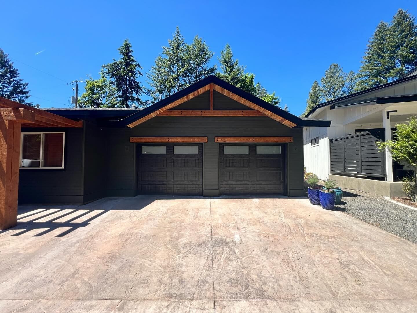 Modern house with double garage and wide concrete driveway under a blue sky