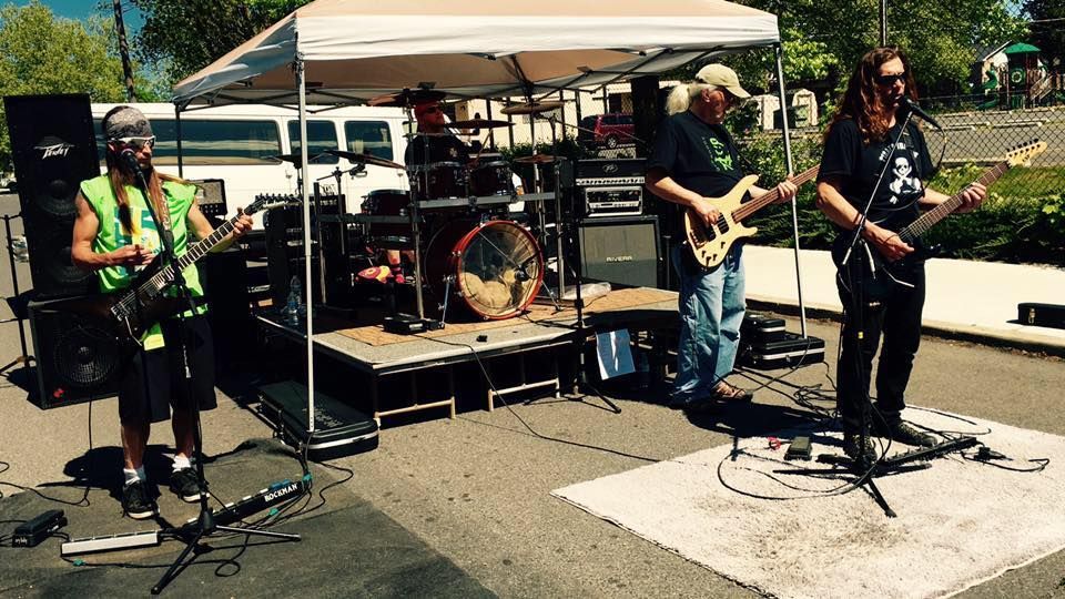 Band playing outdoors under a canopy. Musicians with instruments on a stage in a parking lot.