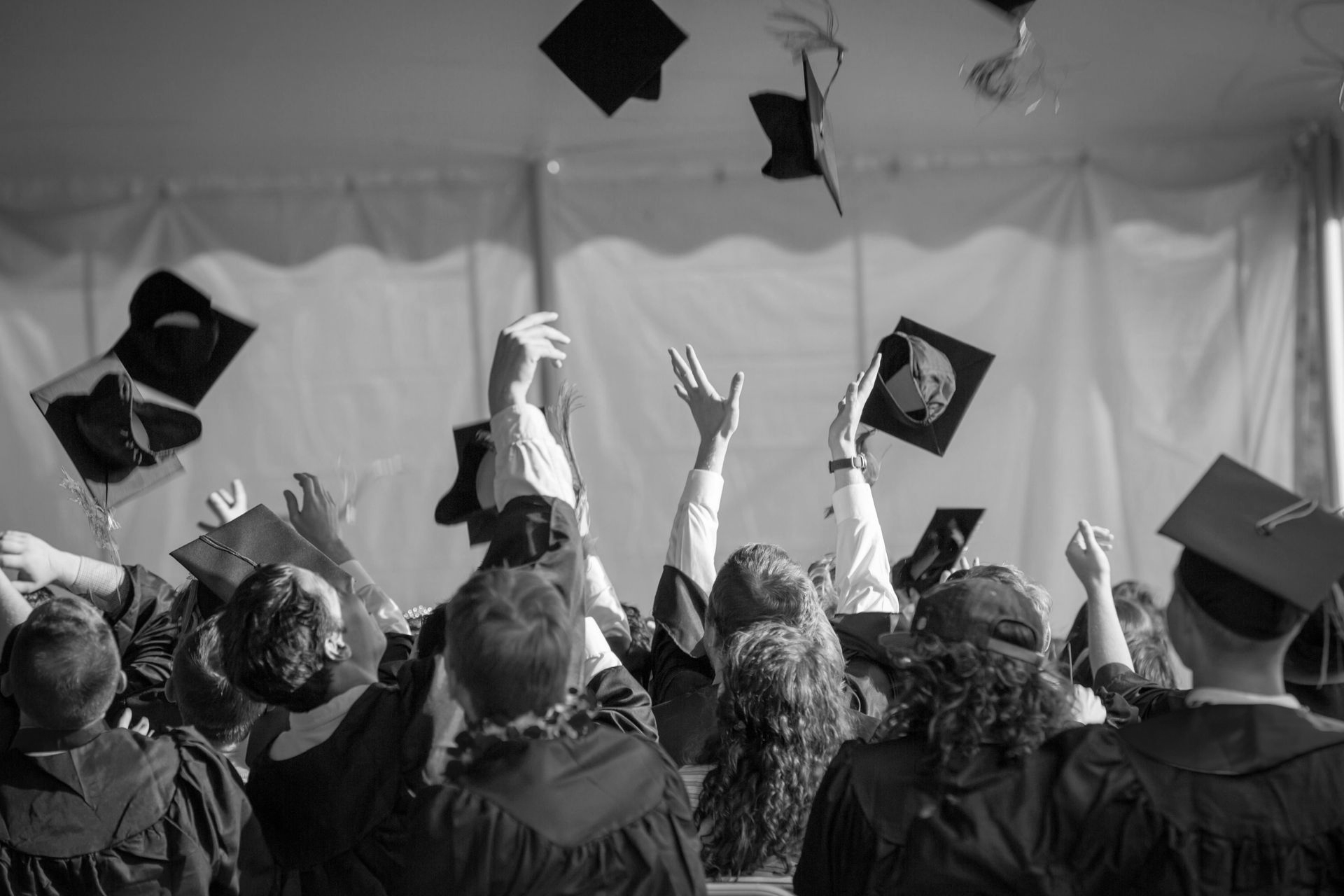 Graduation ceremony: Students in caps and gowns throwing mortarboards in the air.