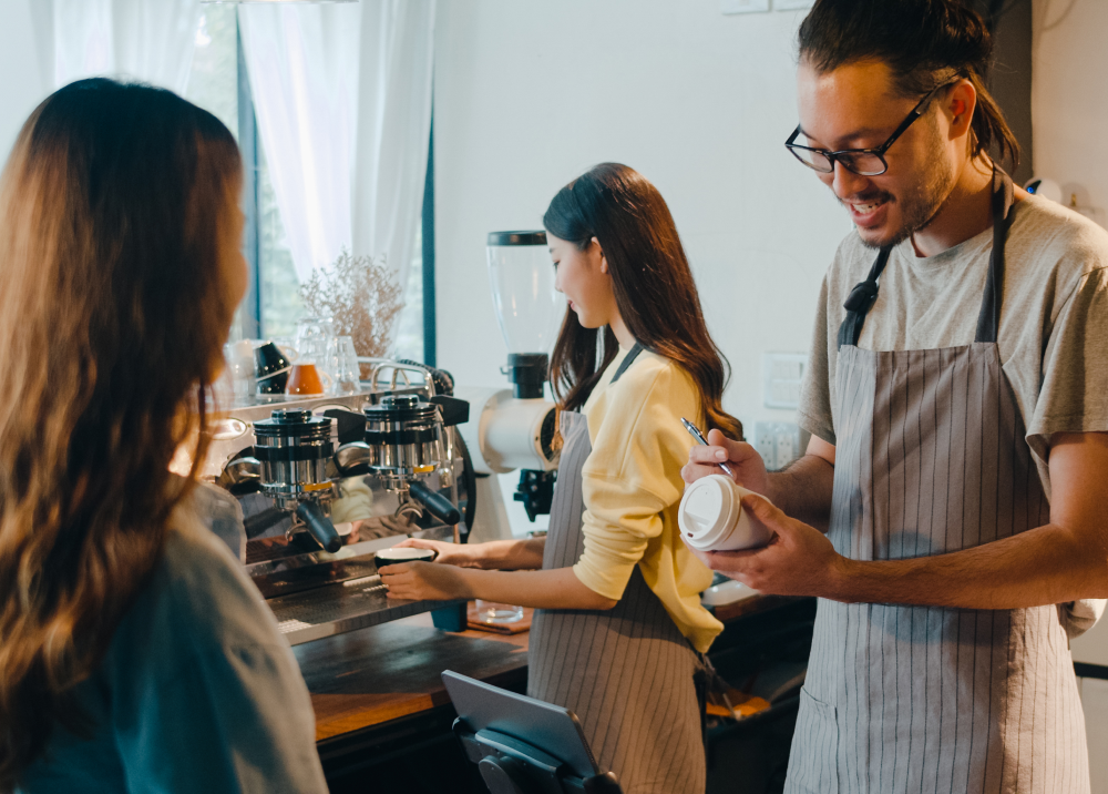 A man is serving a cup of coffee to a woman in a coffee shop.