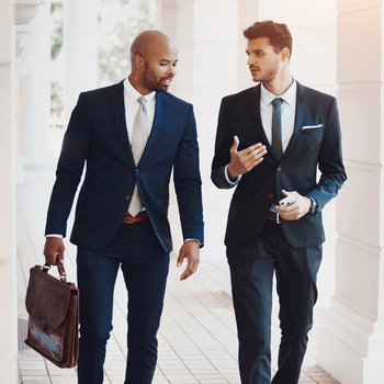 Two men in suits and ties are walking down a hallway