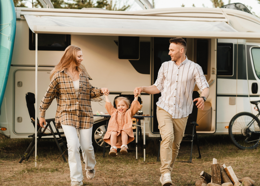 A family is walking in front of a rv holding hands.