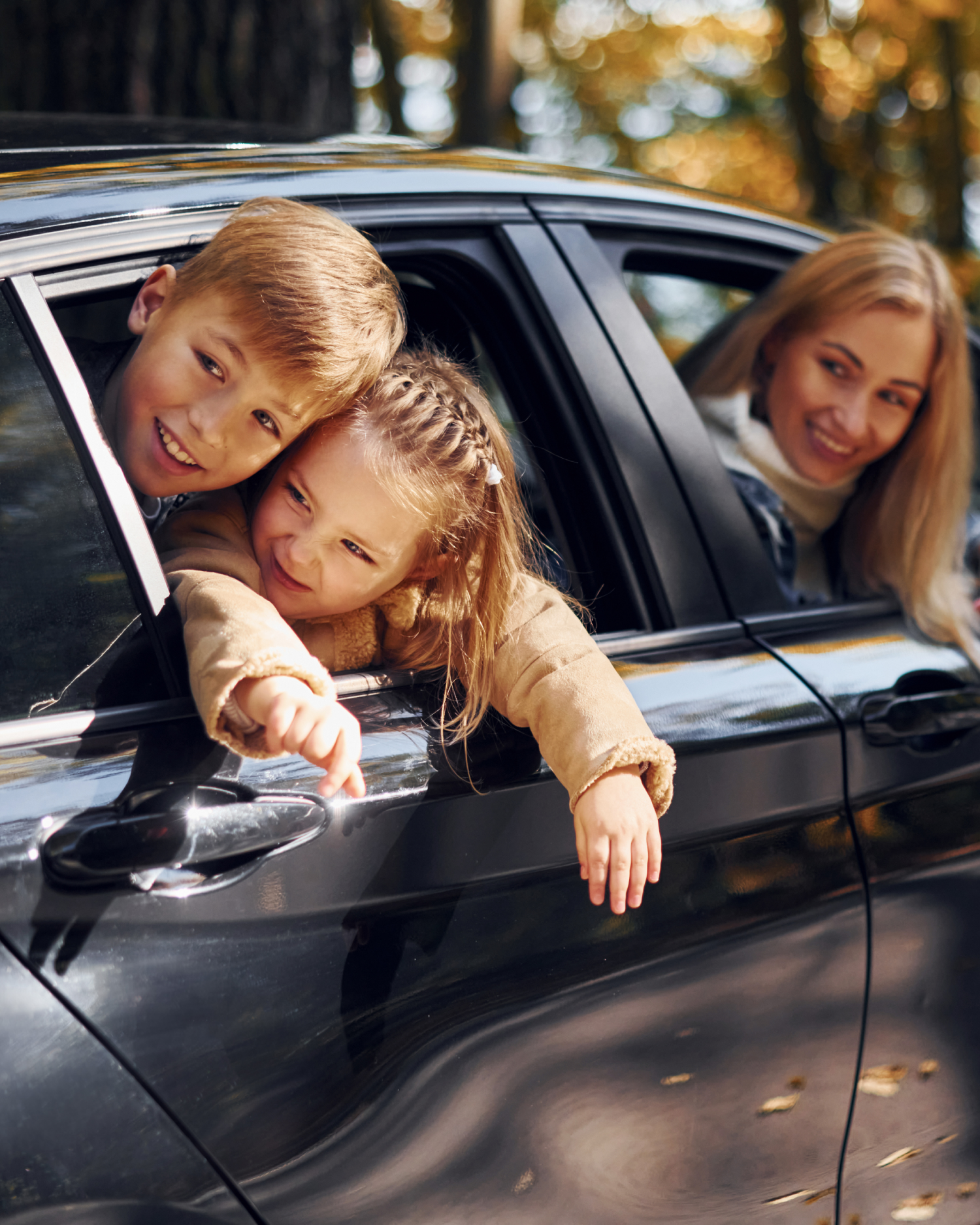 A boy and a girl are sticking their heads out of a car window.