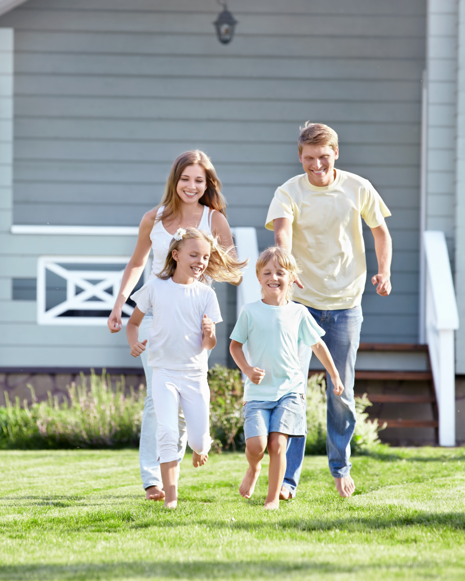 A family is running in the grass in front of a house.