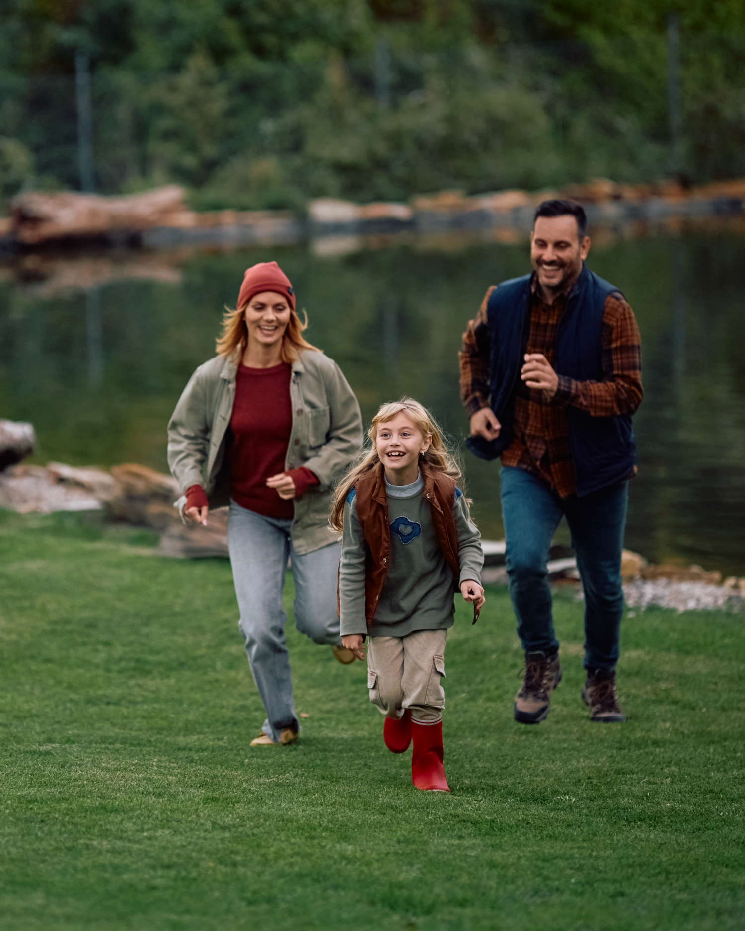 A family is running in a park near a lake.