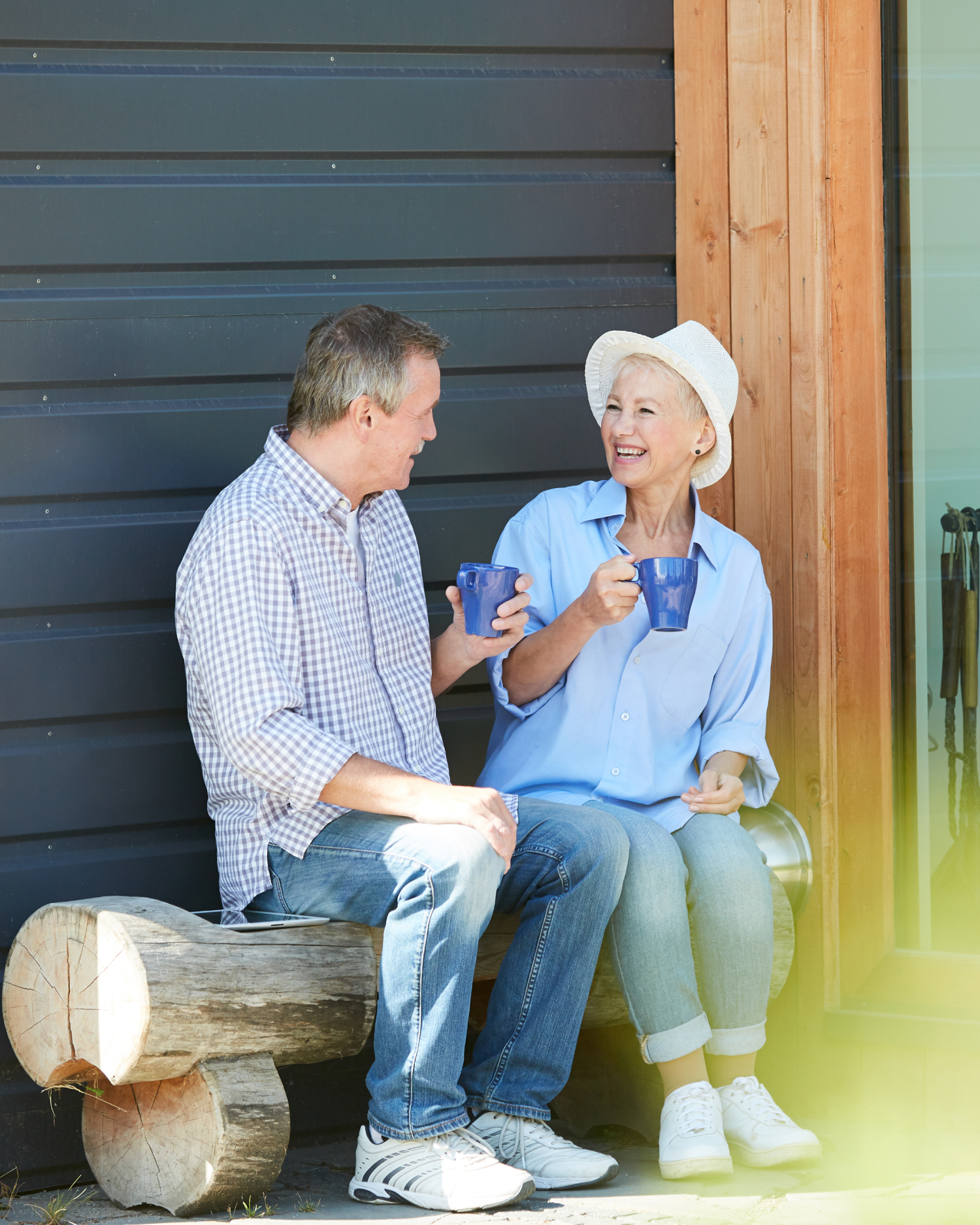 A man and a woman are sitting on a bench drinking coffee.