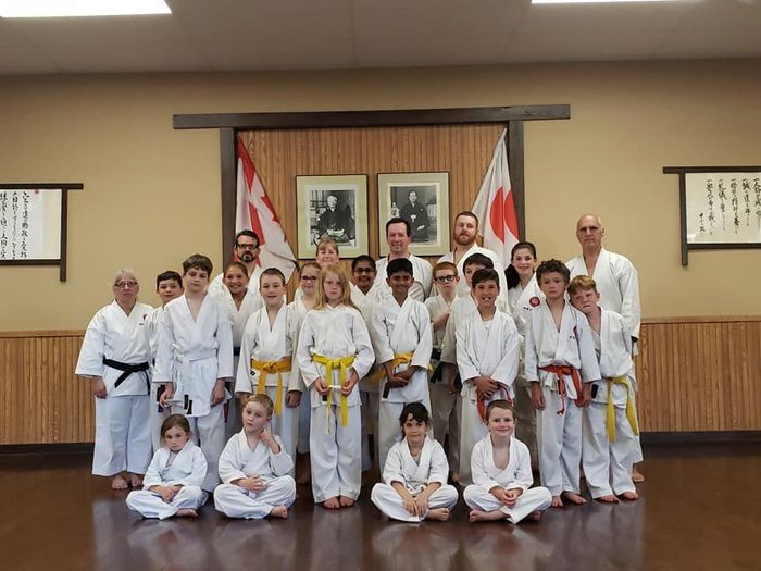 A group of people in karate uniforms are posing for a picture in a gym.