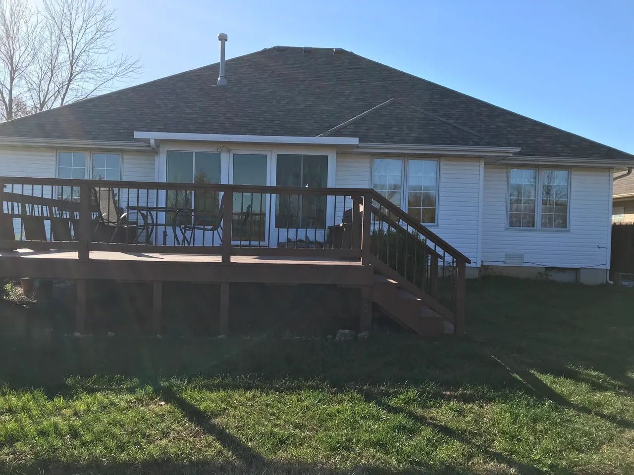 The back of a house with a wooden deck and stairs.