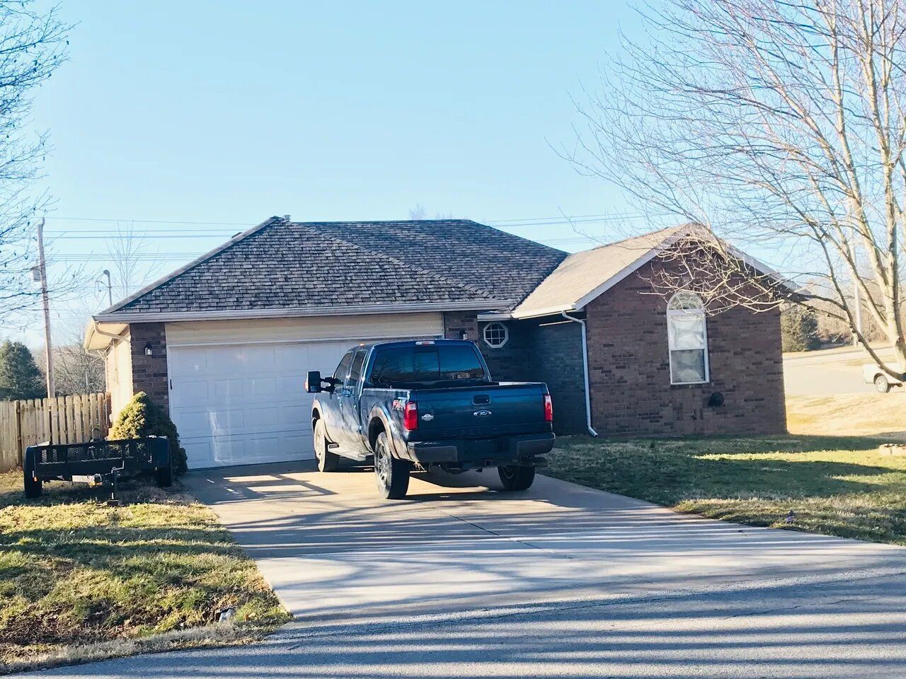 A blue truck is parked in front of a brick house.