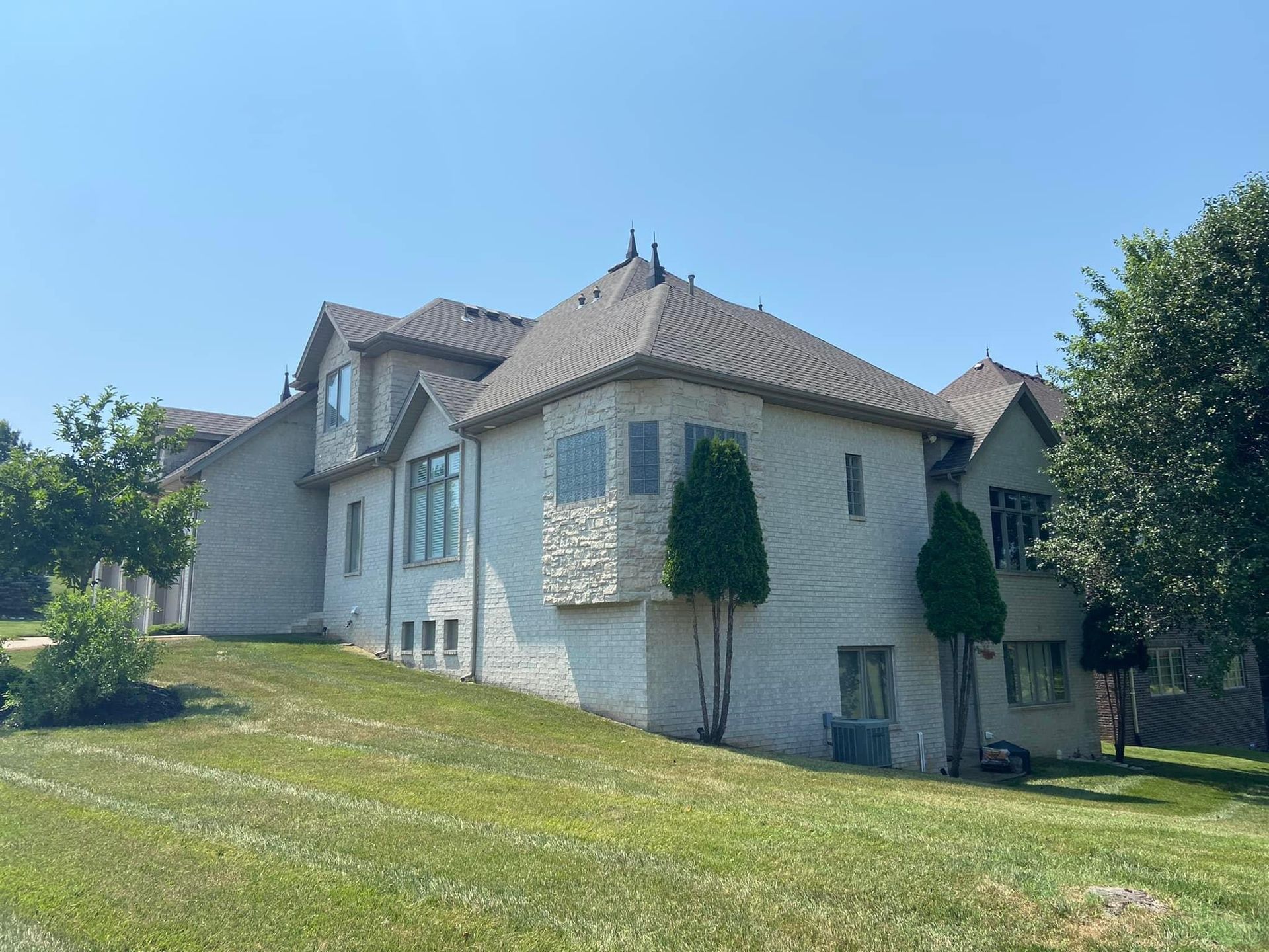 A large white house is sitting on top of a lush green hill.