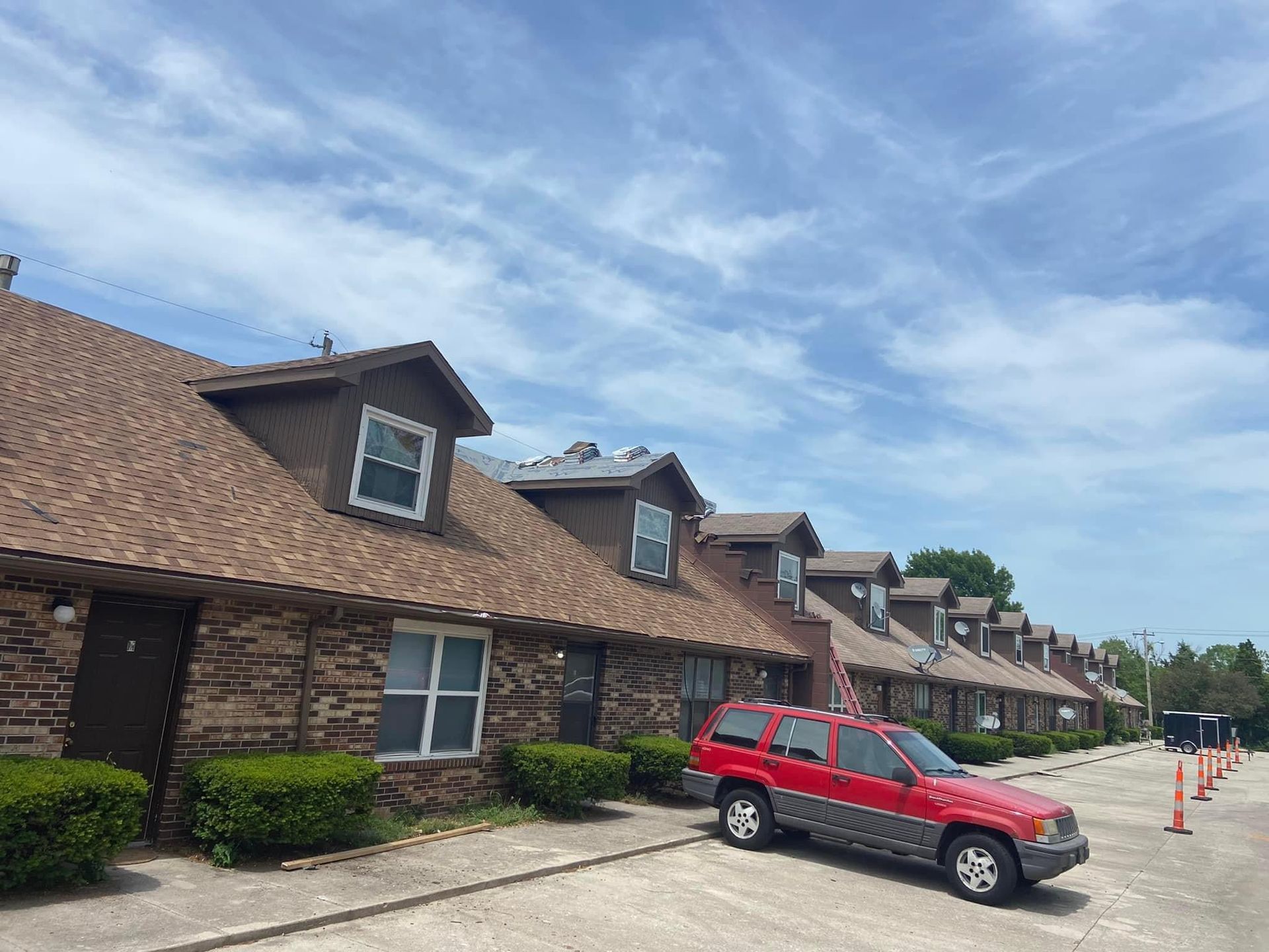 A red suv is parked in front of a row of apartment buildings.