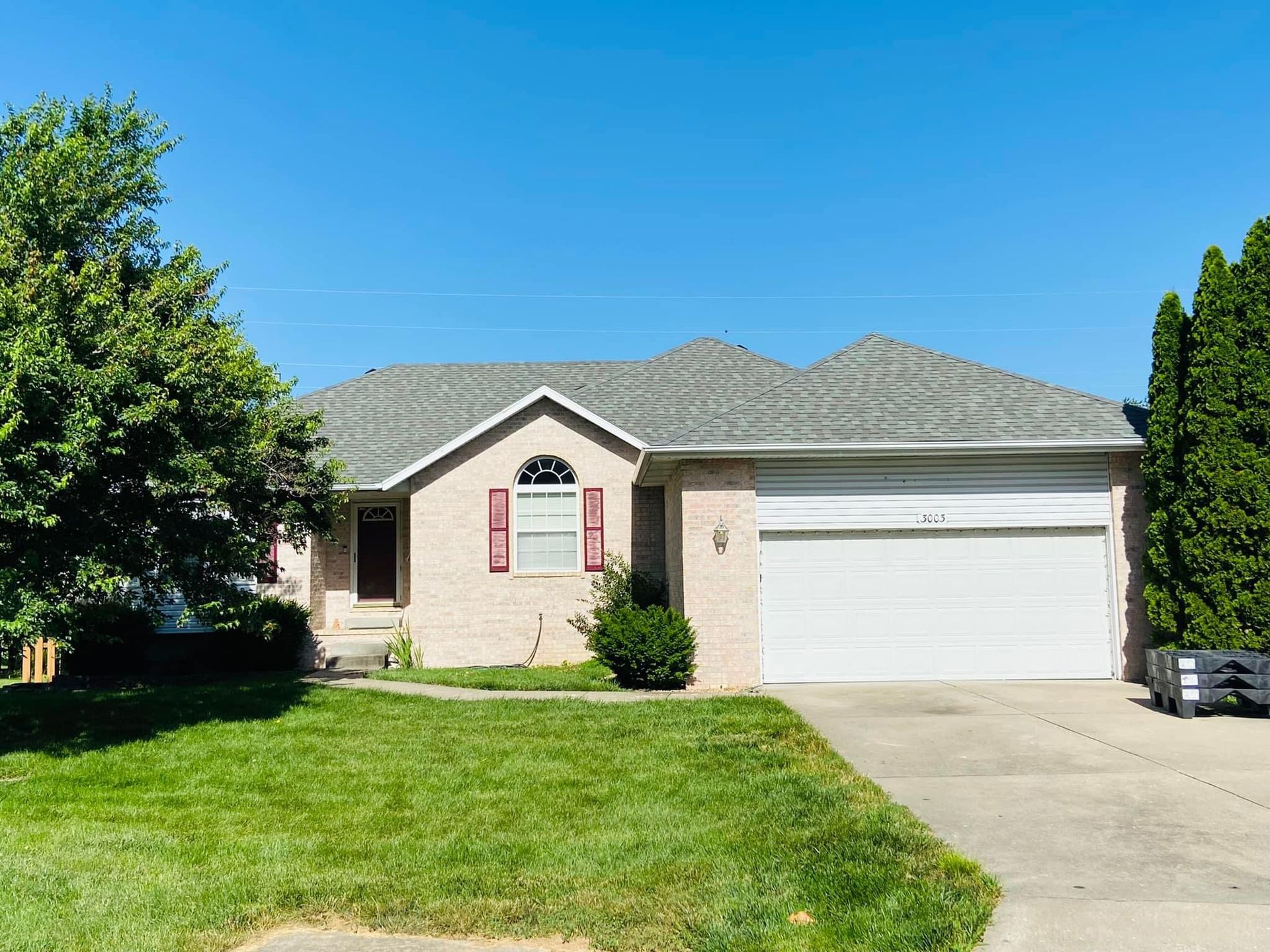A brick house with a white garage door and a car parked in front of it.