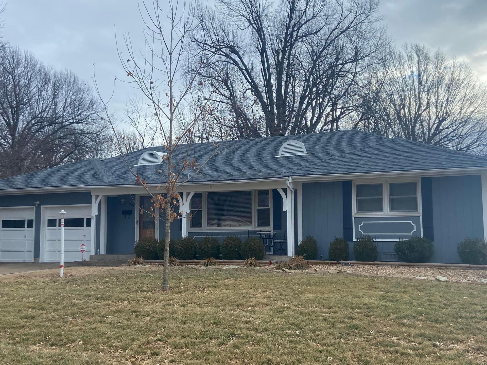 A blue house with a white garage door and a blue roof.